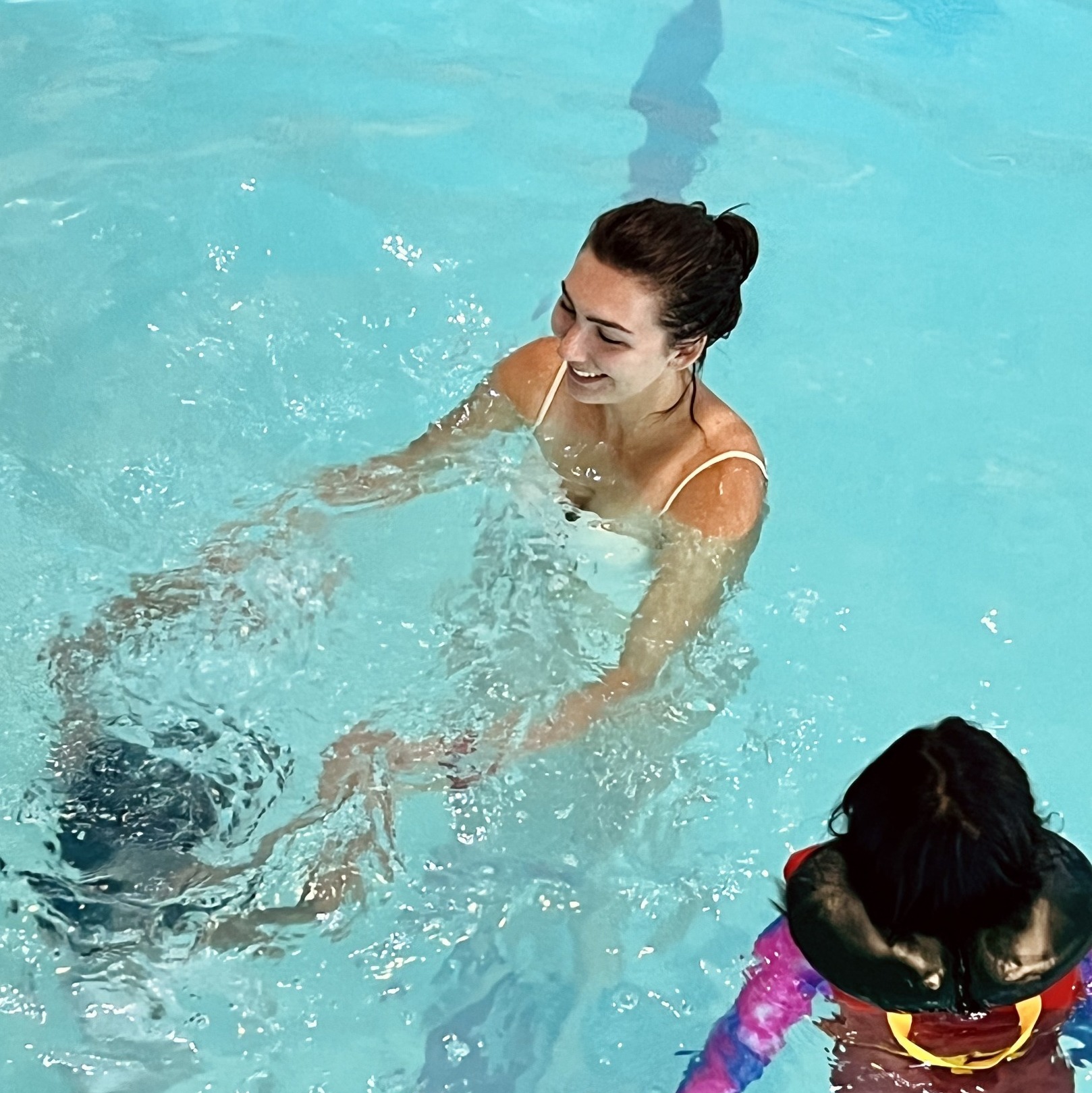 An adult with two kids playing in a pool