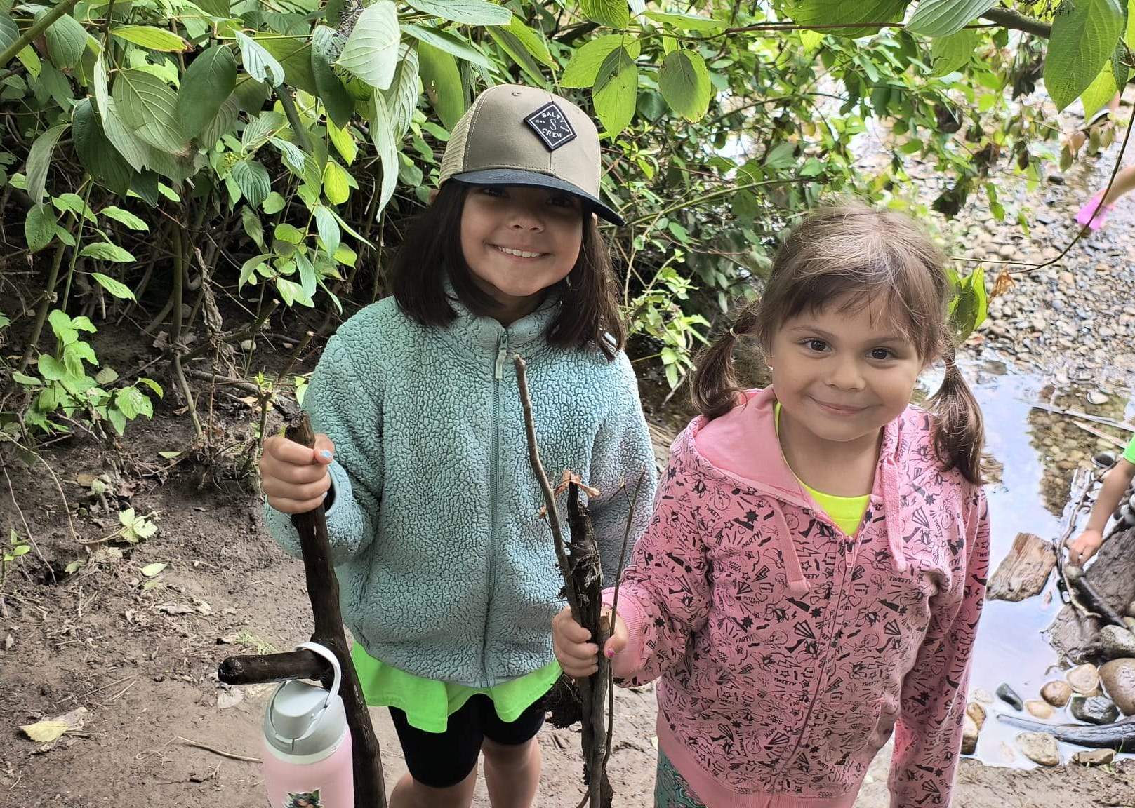 two campers holding sticks in the forest